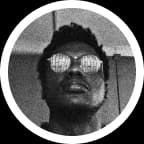 A grainy monochrome shot of Godwin in mirrored sunglasses, chin up